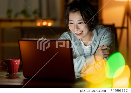 晚上在客廳裡觀看視頻的年輕女子 晚上在客廳裡觀看視頻的年輕女子 74996512