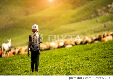 young hiker drinking water at mountain valley 74997203