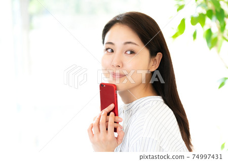 Young woman looking at a smartphone Young woman looking at a smartphone 74997431