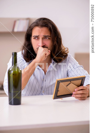 Young man drinking alcohol at home in unhappy love concept Young man drinking alcohol at home in unhappy love concept 75000892