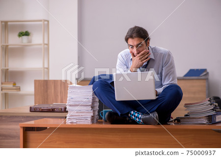 Young male employee unhappy with excessive work in the office 75000937