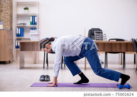 Young male employee doing sport exercises during break Young male employee doing sport exercises during break 75001624