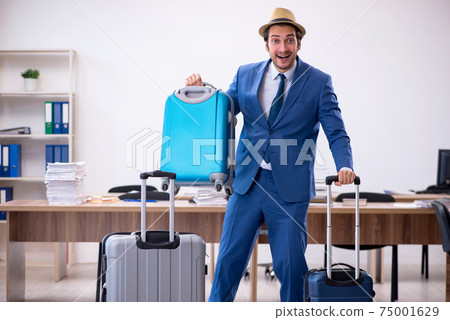 Young male employee preparing for trip in the office 75001629