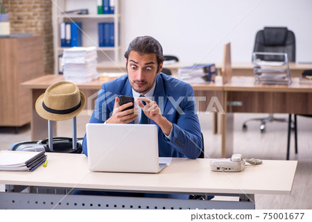 Young male employee preparing for trip in the office 75001677
