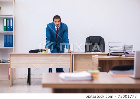 Young male employee working at workplace Young male employee working at workplace 75001778