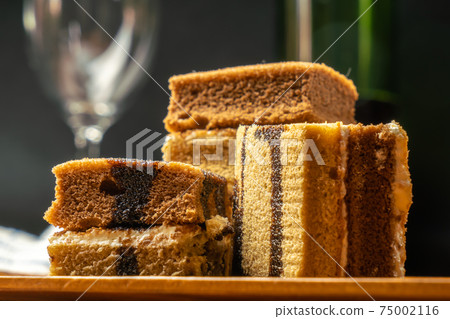 Closeup of Mocha sponge layer cake on wooden tray with wine and wine glass. 75002116