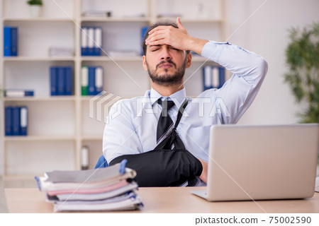 Young arm injured male employee working in the office Young arm injured male employee working in the office 75002590