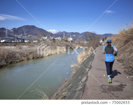 A woman jogging on a riverbed course A woman jogging on a riverbed course 75002655