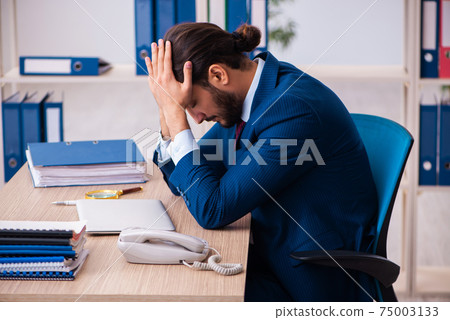 Young male employee and too many work in the office 75003133
