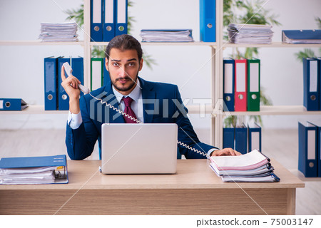 Young male employee and too many work in the office Young male employee and too many work in the office 75003147