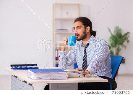 Young male employee drinking coffee during break Young male employee drinking coffee during break 75003765