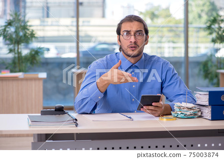 Young male bookkeeper in budget planning concept Young male bookkeeper in budget planning concept 75003874