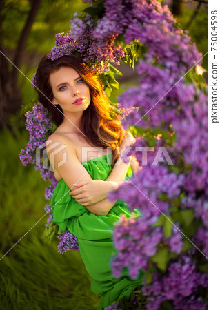 attractive woman in green dress posing near lilac flower attractive woman in green dress posing near lilac flower 75004598