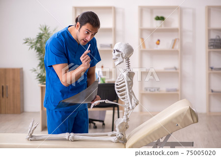 Young male doctor and skeleton patient in antismoking concept 75005020