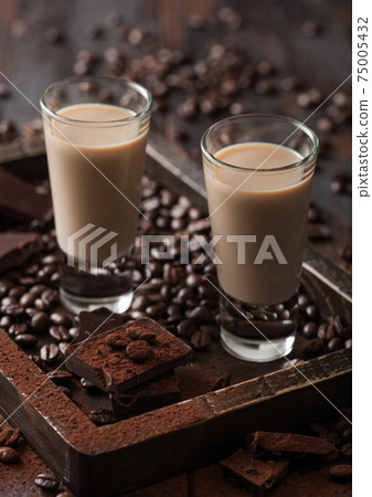 Irish cream baileys liqueur in shot glasses in wooden tray with coffee beans and powder  75005432
