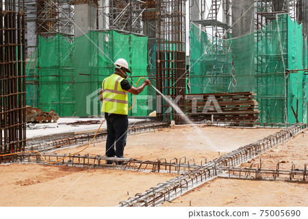 KUALA LUMPUR, MALAYSIA -JULY 30, 2020: Construction workers mixing and spraying the anti termite chemical treatment to the soil at the construction site.  75005690
