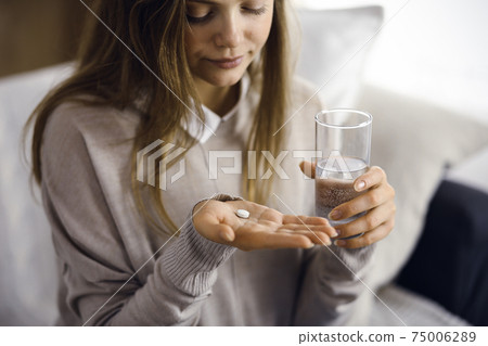 Close-up woman holding pills time to take medications, cure for headache, high blood pressure or cholesterol level remedy pain killer drugs. Stay at home concept during Coronavirus pandemic and self 75006289