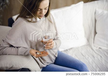 Close-up woman holding pills time to take medications, cure for headache, high blood pressure pain killer drugs at home. Stay at home concept during Coronavirus pandemic 75006295