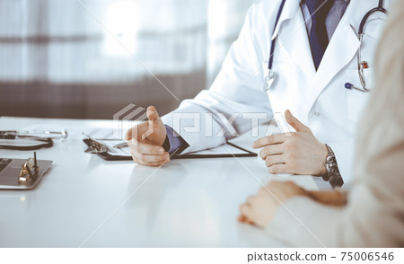 Unknown male doctor and patient woman discussing something while sitting in clinic and using clipboard. Best medical service in hospital, medicine, pandemic stop Unknown male doctor and patient woman discussing something while sitting in clinic and using clipboard. Best medical service in hospital, medicine, pandemic stop 75006546