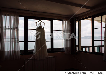 a wedding dress hanged on a sea view window a wedding dress hanged on a sea view window 75006682