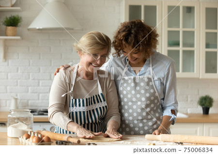 Adult daughter and retired mom make dough for bakery together Adult daughter and retired mom make dough for bakery together 75006834