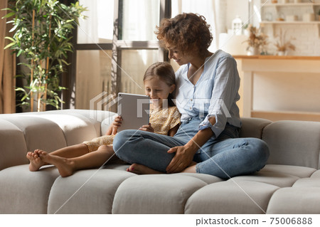 Affectionate mother shopping from home with daughter kid using pad 75006888