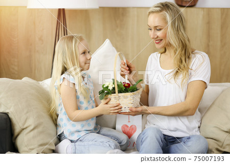 Happy mother day. Child daughter congratulates mom and gives her basket of spring flowers. Family concept 75007193