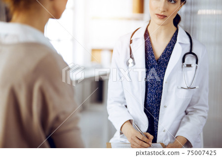 Doctor and patient discussing current health examination while sitting in sunny clinic. Medicine concept 75007425