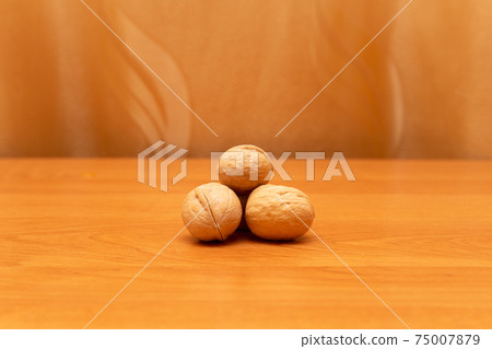 Walnuts on the orange table. Golden background, much space around Walnuts on the orange table. Golden background, much space around 75007879