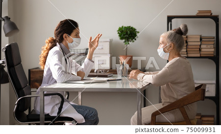 Side view doctor wearing face mask consulting mature patient Side view doctor wearing face mask consulting mature patient 75009931