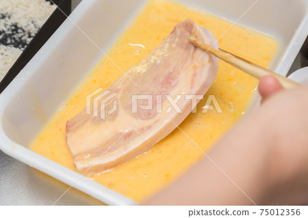 Hands of a woman preparing pork cutlet 75012356