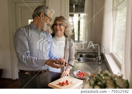 Happy middle aged couple of vegans cooking dinner together Happy middle aged couple of vegans cooking dinner together 75012592
