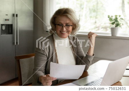 Happy adult retiree woman reading bank document 75012631