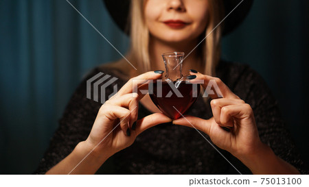 Cropped image of woman holding heart shaped glass jar of love potion 75013100