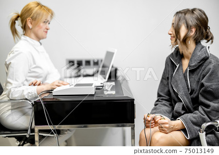 Woman takes hold of the brass handpieces of bioenergetic testing device 75013149