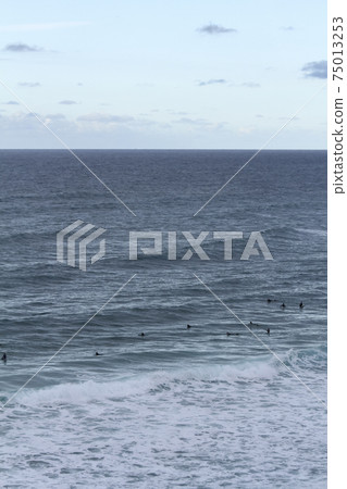 Many surfers sit and lie on their surfboards between breaking approaching waves on a beach in Portugal on the Atlantic Ocean Many surfers sit and lie on their surfboards between breaking approaching waves on a beach in Portugal on the Atlantic Ocean 75013253