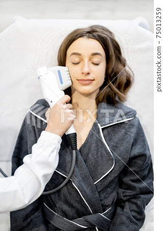 Woman on ultrasound face lifting procedure in cosmetology salon Woman on ultrasound face lifting procedure in cosmetology salon 75013259