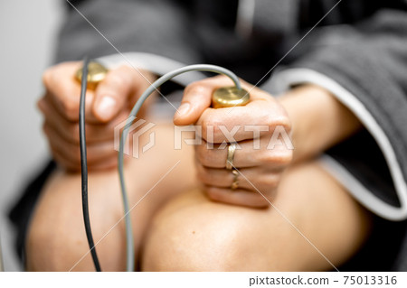 Woman takes hold of the brass handpieces of bioenergetic testing device 75013316