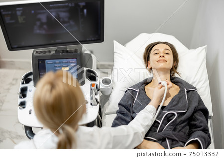 Doctor examining thyroid of female patient with ultrasound scan in clinic Doctor examining thyroid of female patient with ultrasound scan in clinic 75013332