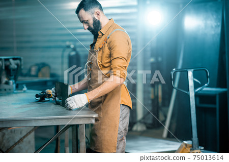 Man working with metal at the workshop 75013614