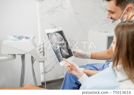 Dentist showing x-ray of a skull for young patient 75013618