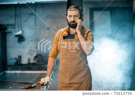 Welder with phone at the workshop 75013759