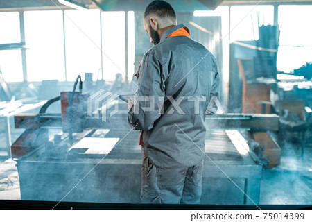 Heavy industry worker controlling the process of metal cutting Heavy industry worker controlling the process of metal cutting 75014399