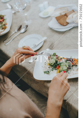 There is a salad close-up. hands properly hold cutlery in the restaurant. table etiquette. 75015602