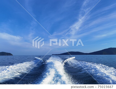 Blue waves in the ocean behind speedboat Blue waves in the ocean behind speedboat 75015687