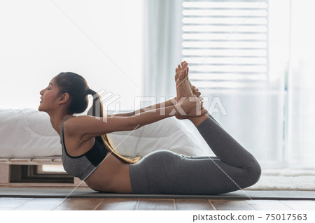 Athletic Asian woman practice yoga bow or dhanurasana pose to meditation in bedroom after wake up in the morning Feeling so comfortable and relax,Healthcare Concept Athletic Asian woman practice yoga bow or dhanurasana pose to meditation in bedroom after wake up in the morning Feeling so comfortable and relax,Healthcare Concept 75017563