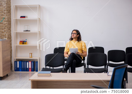 Young male student waiting for teacher in the classroom Young male student waiting for teacher in the classroom 75018000