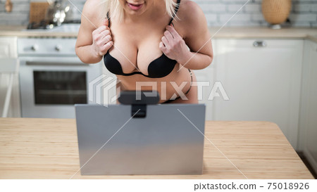 A girl in underwear flirts on an online video connection on a laptop. Woman working as a web cam model 75018926