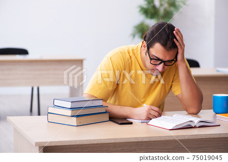 Young male student taking notes during exam preparation 75019045
