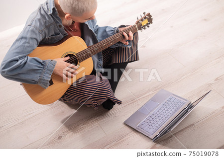 Young hipster woman watching guitar tutorials on laptop. Distance learning music Young hipster woman watching guitar tutorials on laptop. Distance learning music 75019078